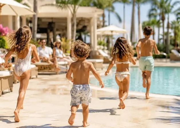 Children and adults walking beside a resort swimming pool