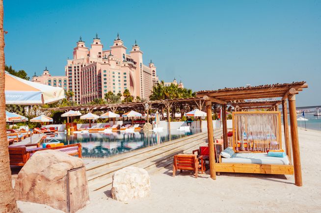 Resort swimming pool with a large pink hotel in the background