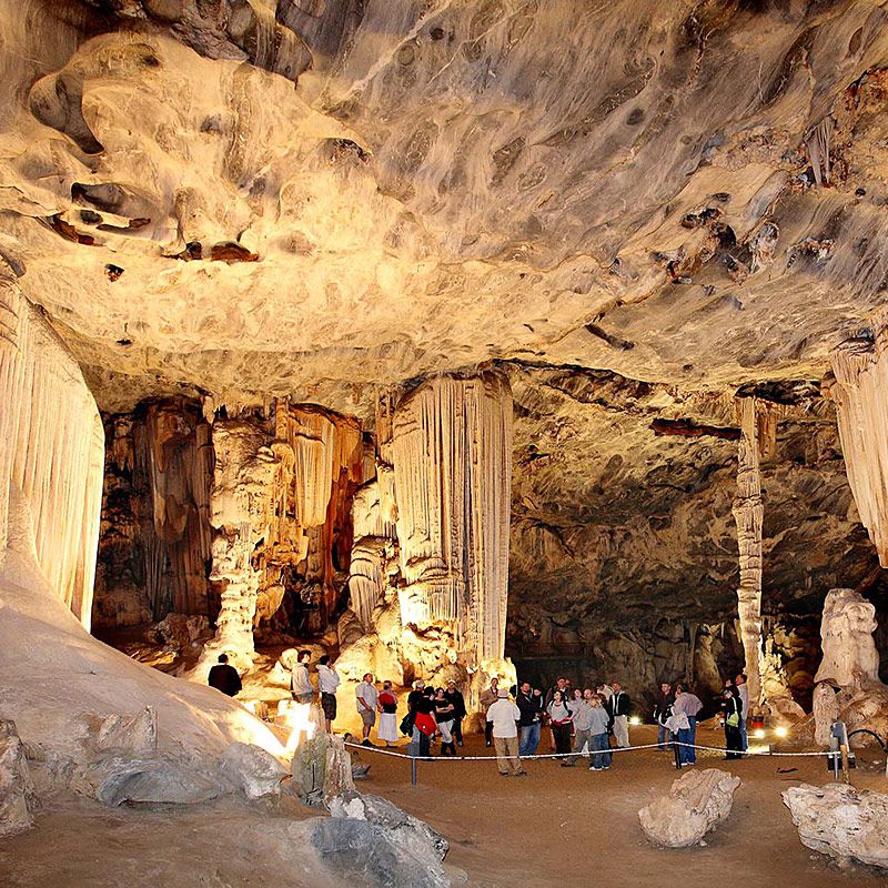 Visitors exploring rock formations inside an illuminated cave