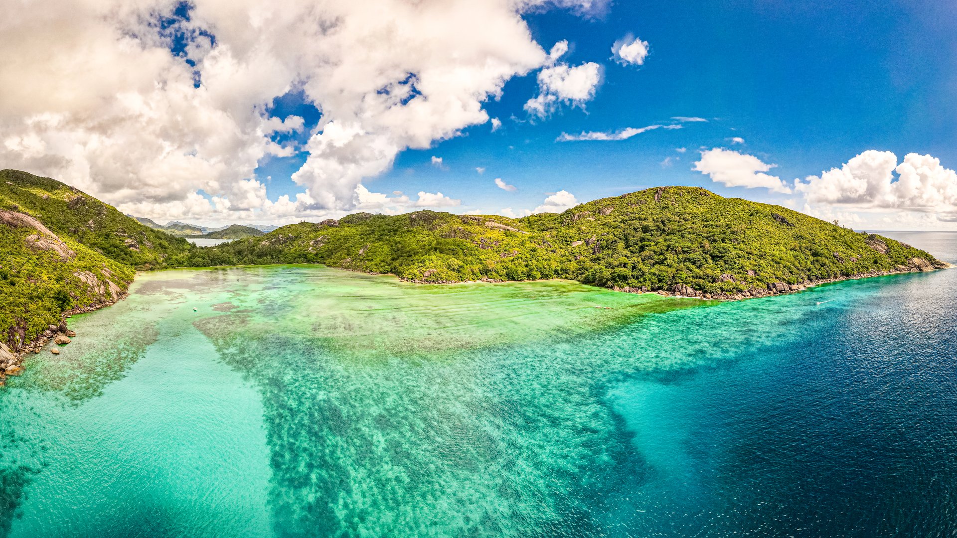 Clear turquoise lagoon beside a green island coastline